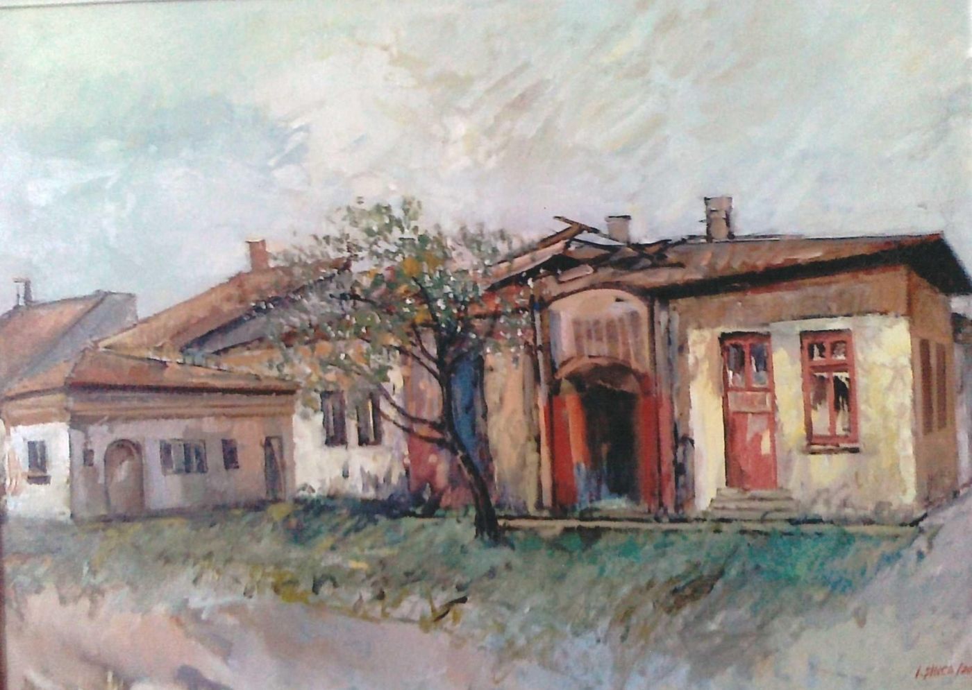 A row of old houses with arched gateways and red windows, along a dirt road.