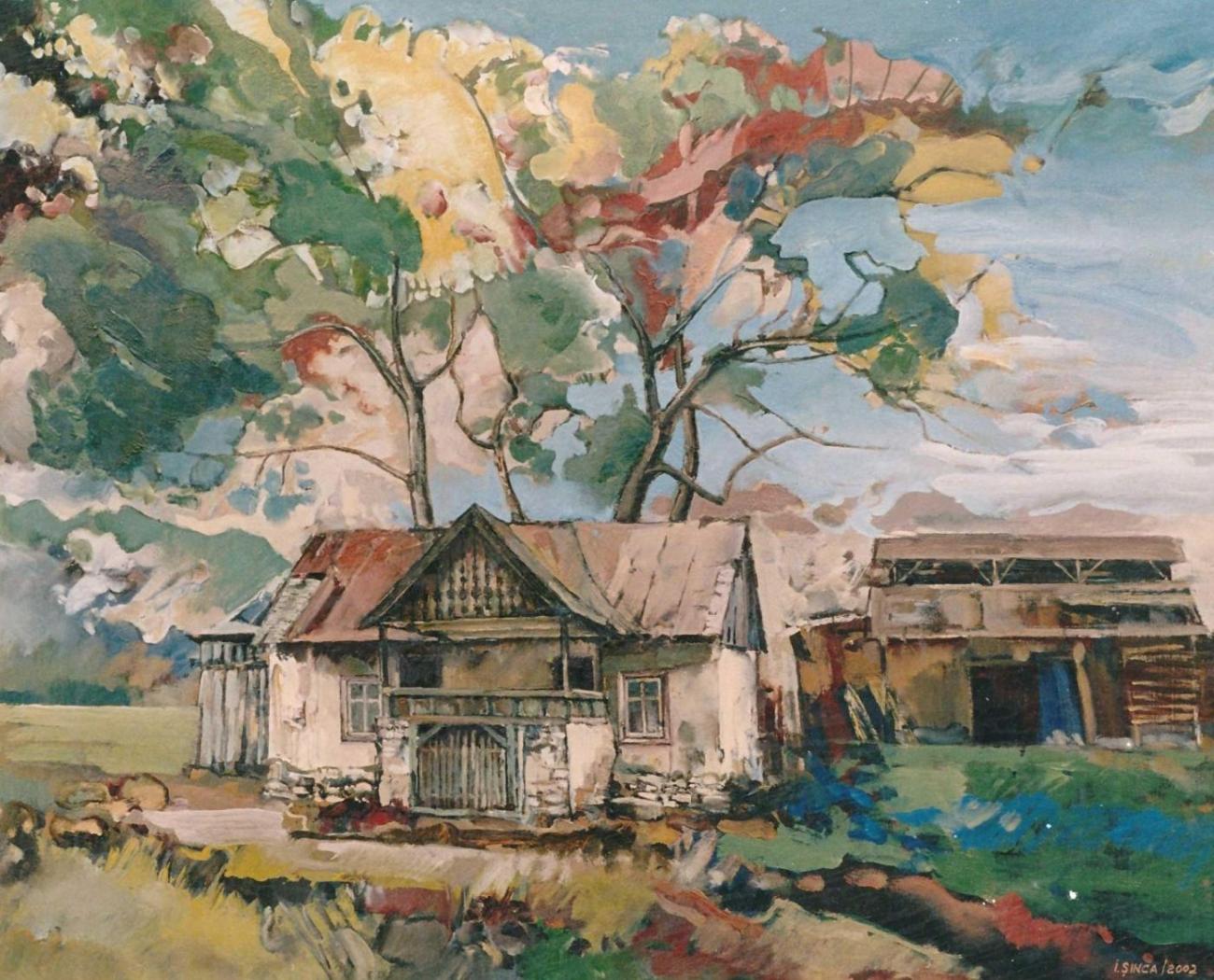 An old house with a hayloft and fretwork gable, beneath two large trees in autumn foliage.