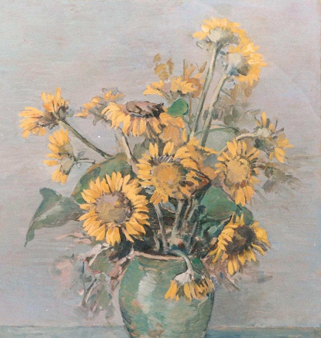 A bunch of sunflowers in a green clay vase against a neutral grey ground.