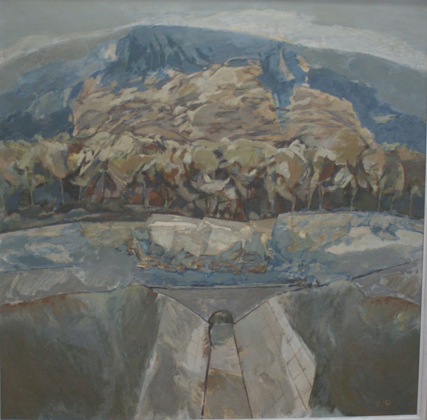 A canal running towards the viewer between stone banks, beneath a blue mountain and a rust-coloured wood.