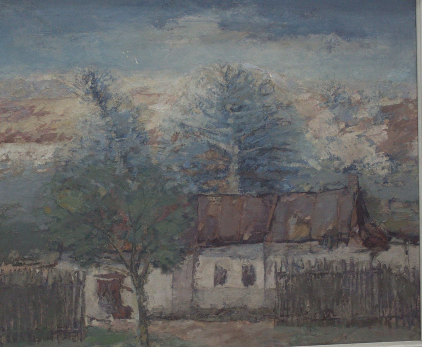 A white house with a brown roof behind a plank fence, with a fruit tree and tall firs at sunrise.