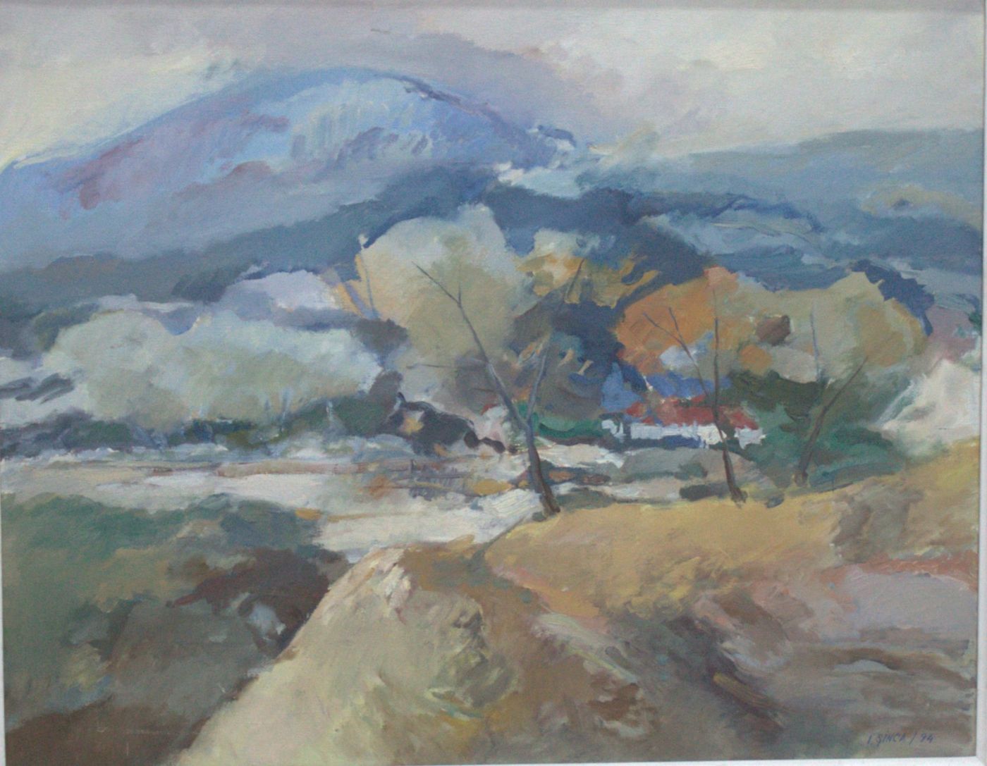 A hill with a clump of autumn trees, a pale road in front and a blue mountain behind.