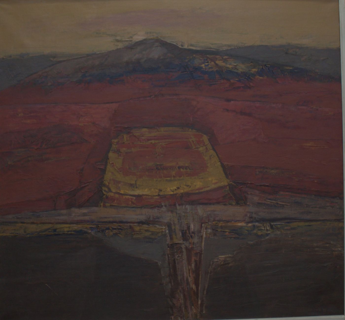 A ravine in deep red with a golden-yellow block at its centre and a black foreground, beneath a blue hill.